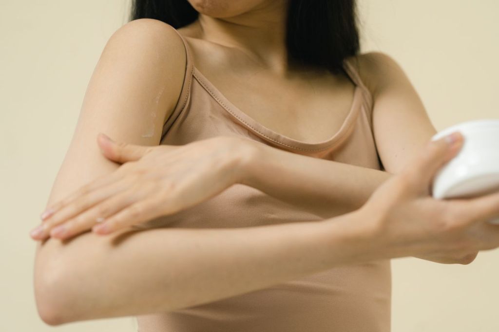 Woman applying moisturiser to her arm